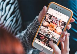 A hand holding a smartphone showing a photo gallery app